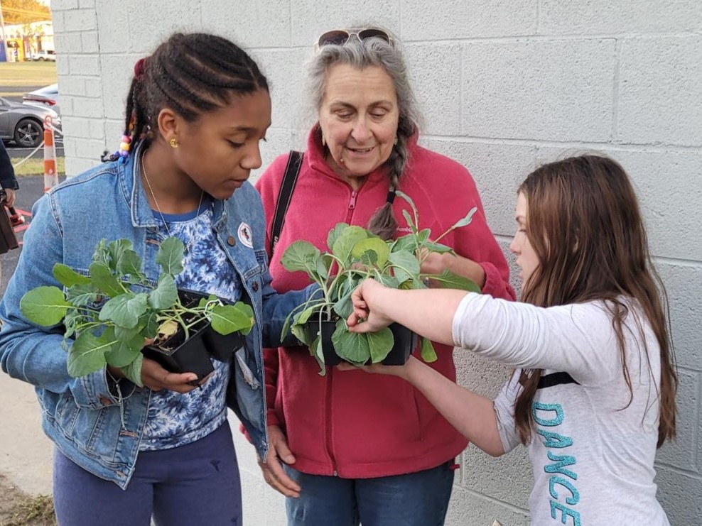 PACE Academy students plant cool-season greens in a school garden with the help of Green Step Schools mentor Jennifer Mancke.